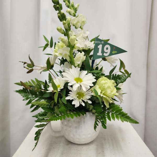 White floral arrangement in a white vase with a small green flag