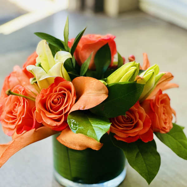 Orange roses and white lilies in a glass vase
