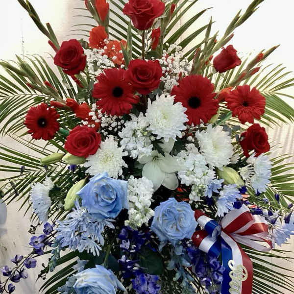 Large red, white, and blue floral standing spray with ribbon