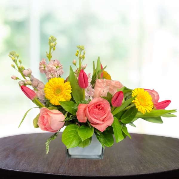 Pink roses and yellow daisies in a square glass vase