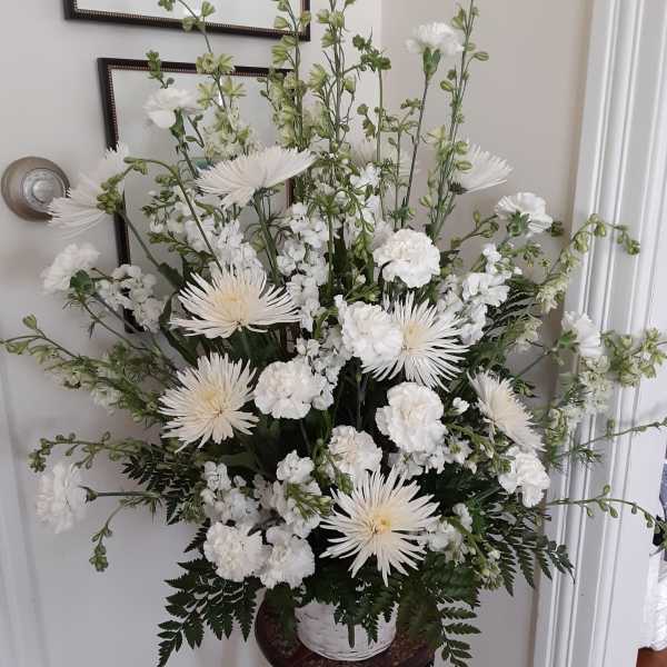 Tall white floral arrangement in a basket on a stand