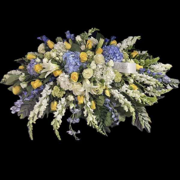 Large floral spray with yellow roses, white lilies, and blue hydrangeas