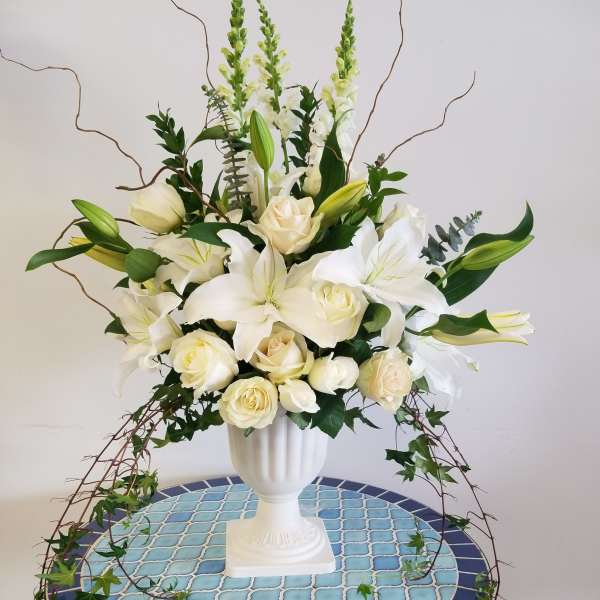 White lilies and cream roses in a white pedestal vase