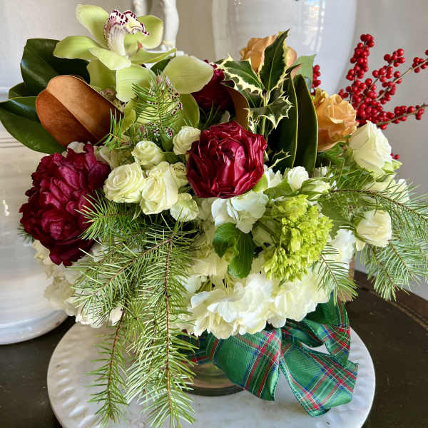 Holiday floral arrangement with red, white, and green blooms in a low vase