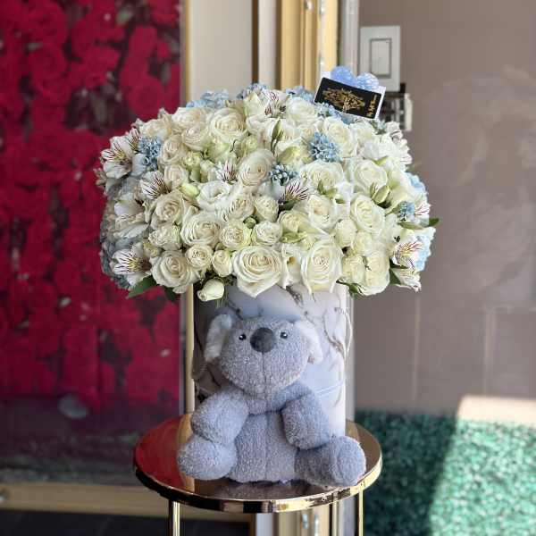 White rose bouquet in a marble box with a gray teddy bear
