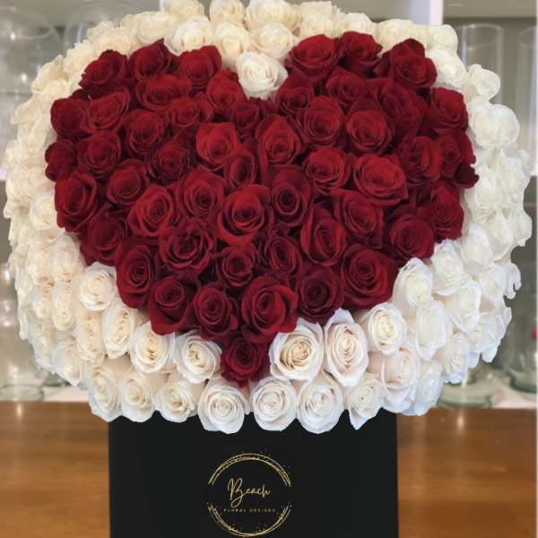 Heart-shaped red and white rose arrangement in a black box