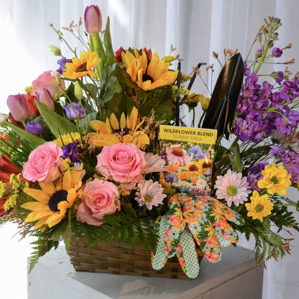 Basket of mixed flowers with a seed packet and gardening gloves