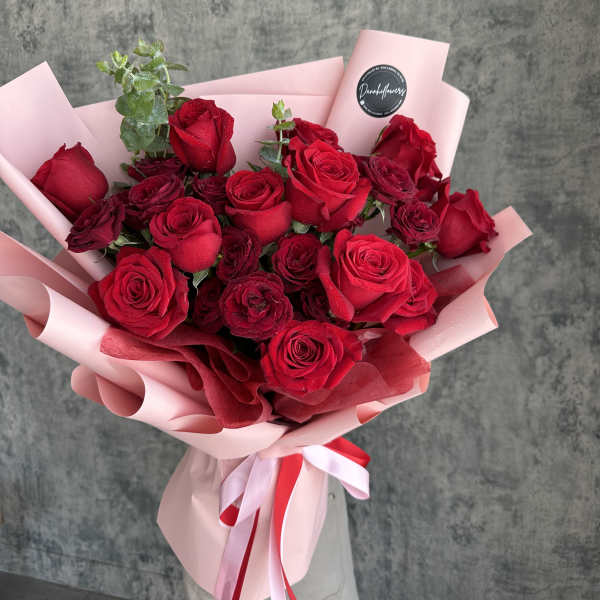 Bouquet of red roses wrapped in pink paper with a ribbon
