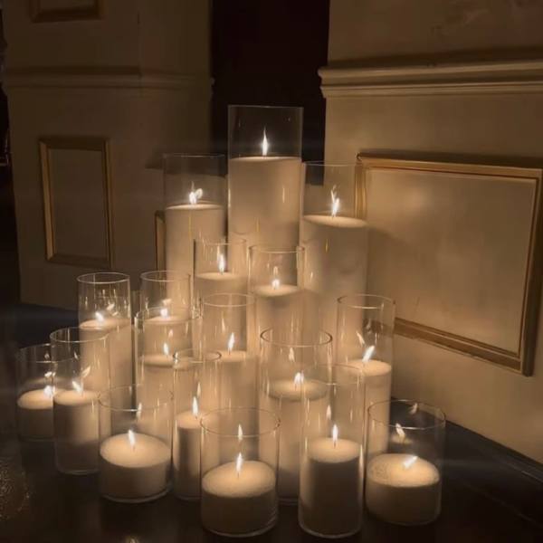 Cluster of lit white pillar candles in clear glass cylinders