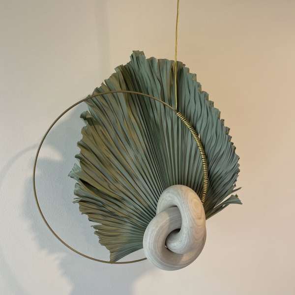 Abstract wall hanging with a dried fan-shaped leaf and circular metal ring
