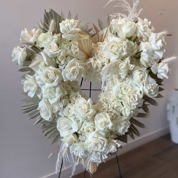 Heart-shaped white rose wreath on a stand