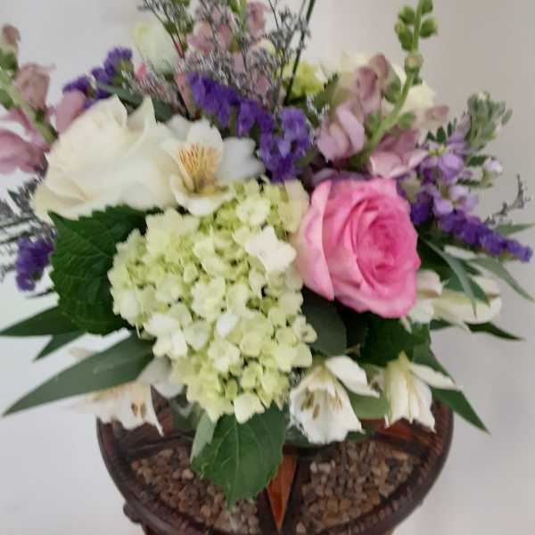 Mixed arrangement with pink rose, white blooms, and green hydrangea in a glass vase