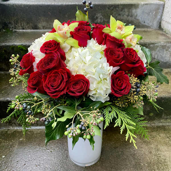 Red roses and white hydrangeas in a white vase with green accents