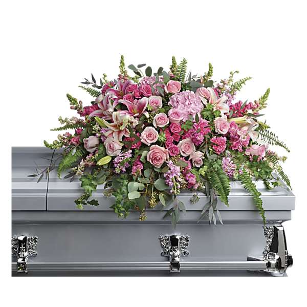 Pink and white casket spray of roses, lilies, and carnations on a silver casket