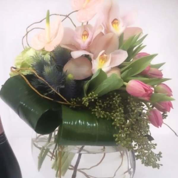 Pink anthuriums and tulips arranged in a clear glass vase
