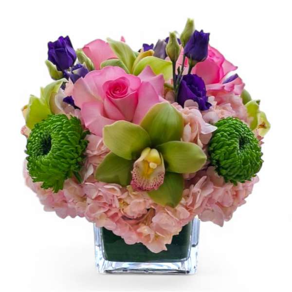 Pink roses and green orchids in a clear square vase