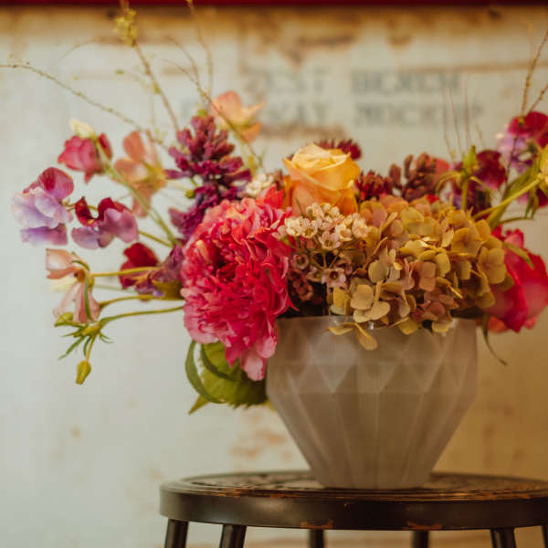 Mixed bouquet of pink, peach, and purple flowers in a gray vase