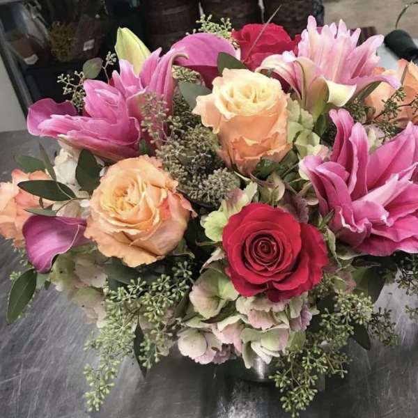 Bouquet of pink lilies and roses with peach roses in a low vase
