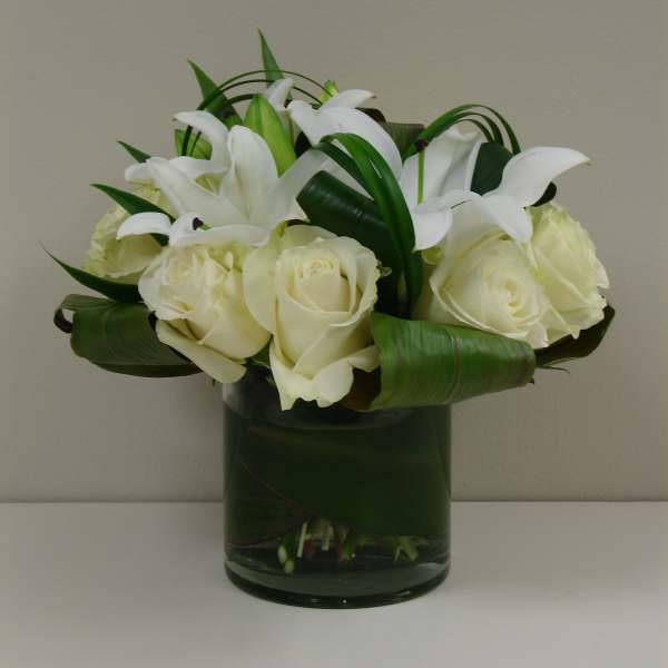 White roses and lilies arranged in a glass vase