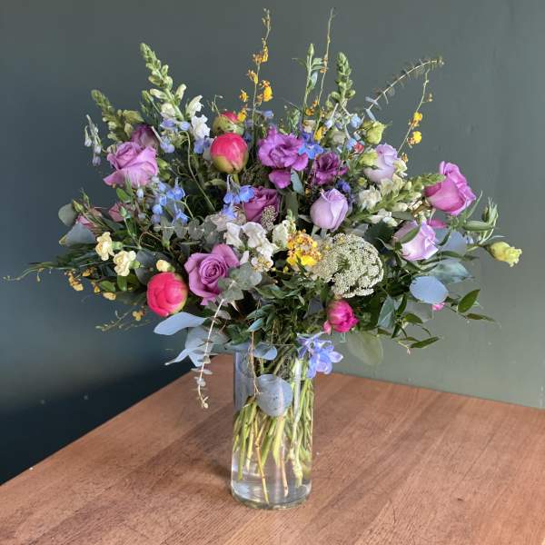 Mixed bouquet of pink and purple flowers in a clear glass vase