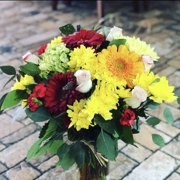 Bouquet of yellow, red, and white flowers in a clear glass vase