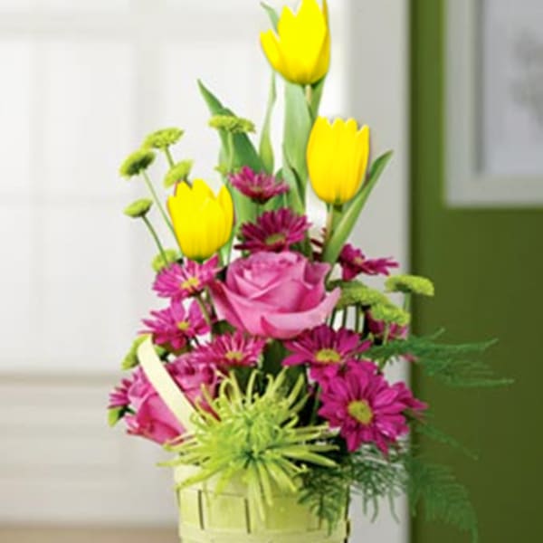 Pink roses and yellow tulips in a green basket vase