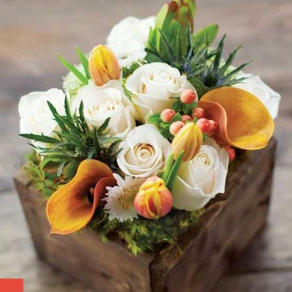 White roses and orange calla lilies in a wooden box