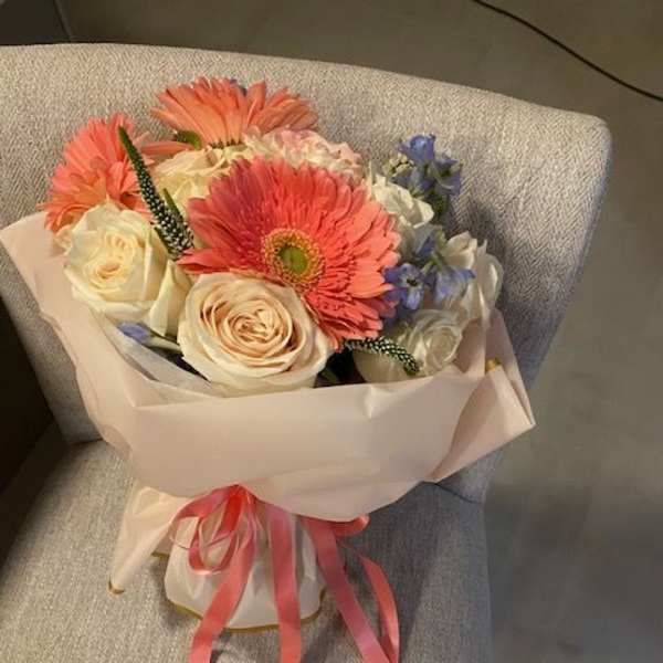 Bouquet of pink gerbera daisies and cream roses wrapped in pale paper