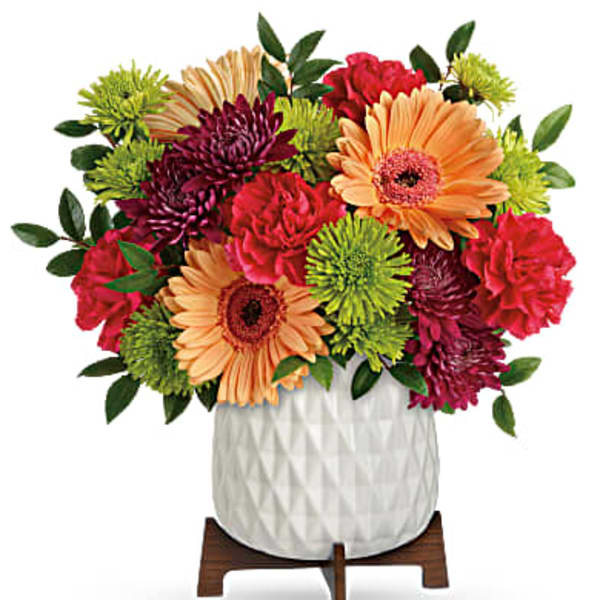 Colorful mixed bouquet in a white textured vase on a wooden stand