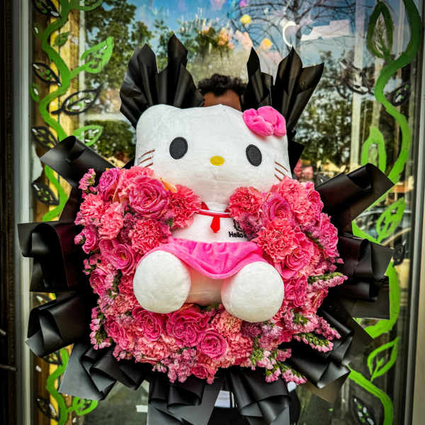 Hello Kitty plush surrounded by a pink flower arrangement