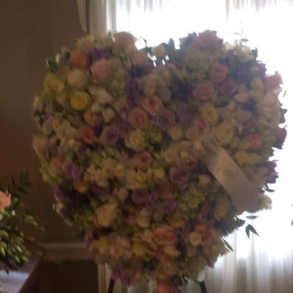 Large heart-shaped floral spray on a stand with pastel roses and mixed blooms