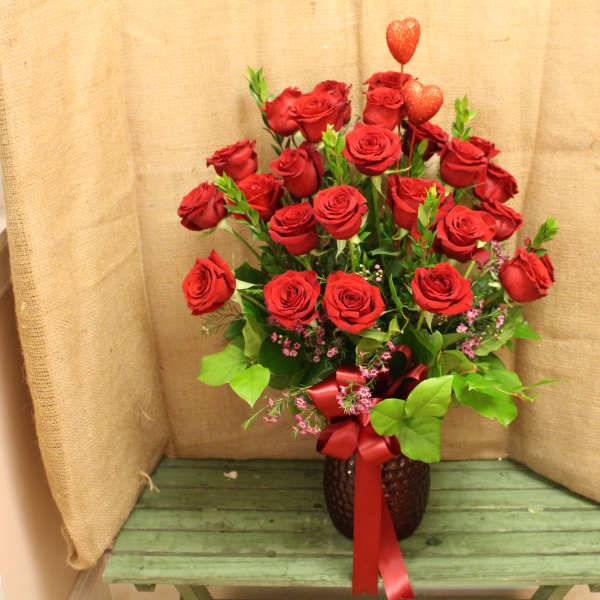 Red roses arranged in a vase with a red ribbon