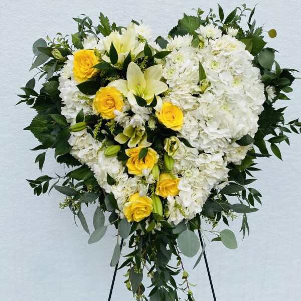 Heart-shaped white and yellow floral spray on a stand