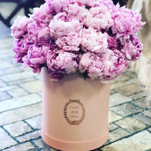 Pink peonies arranged in a blush round box