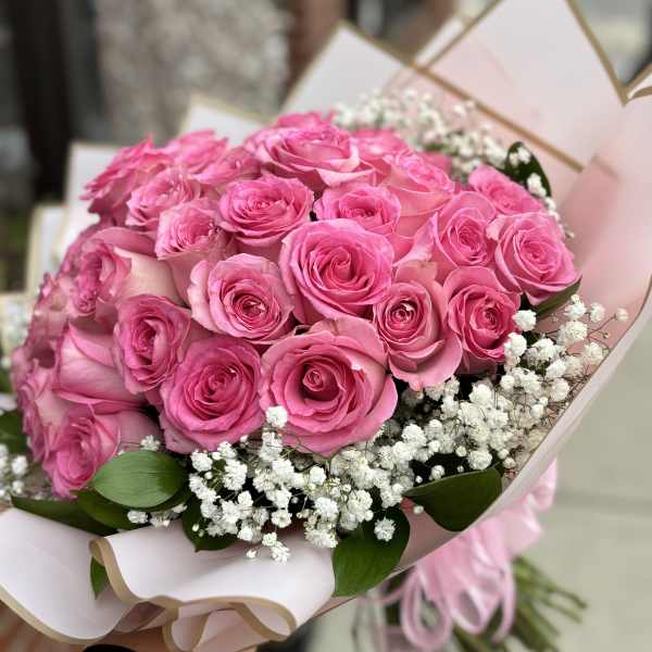 Bouquet of pink roses with white baby's breath in pale pink wrap
