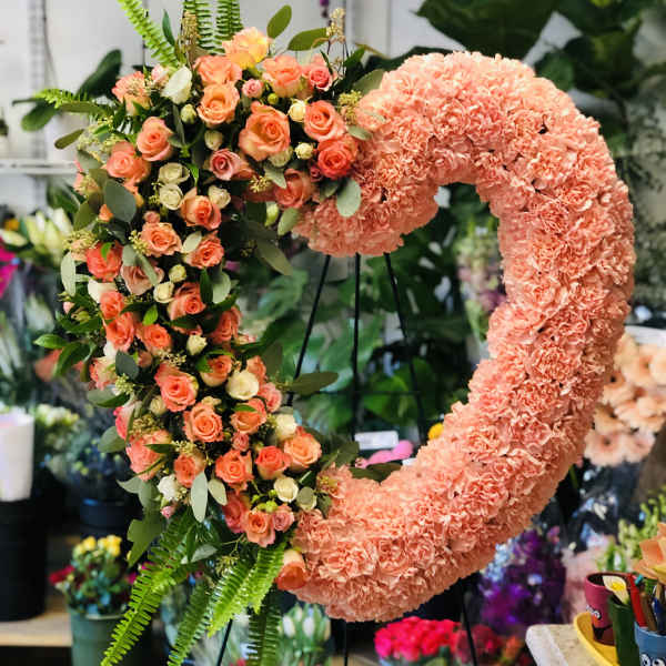Heart-shaped floral wreath with peach roses and pink carnations