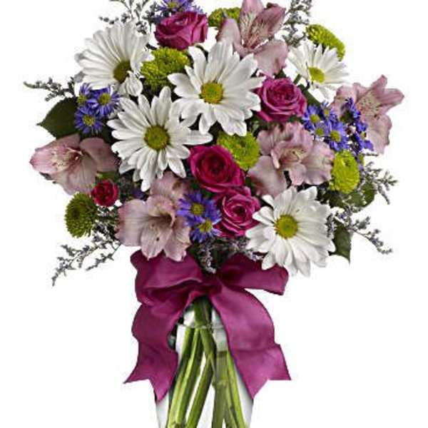 Bouquet of daisies, roses, and alstroemeria in a glass vase with a pink ribbon