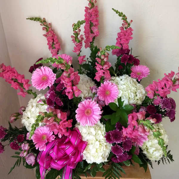 Pink and white floral arrangement with gerbera daisies and snapdragons in a basket