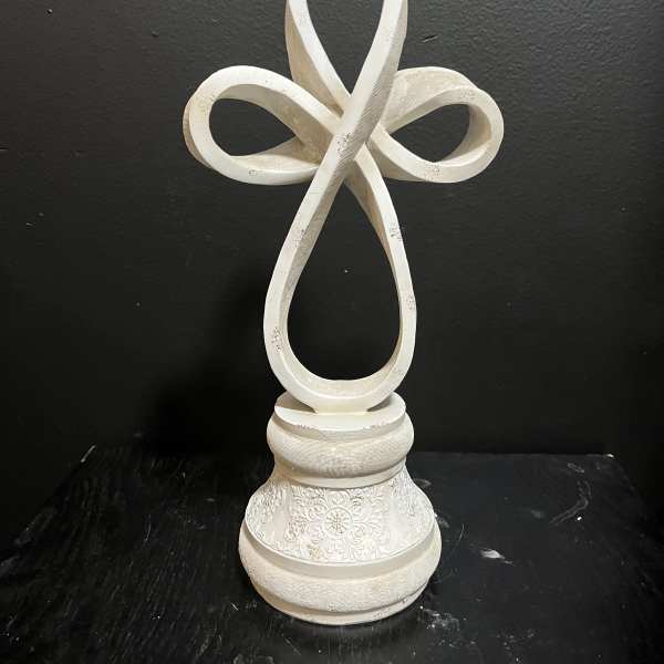 White decorative cross on a carved pedestal base