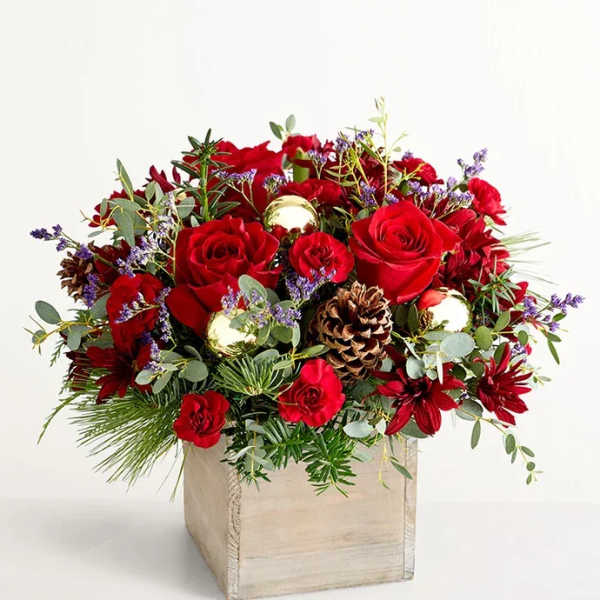 Red roses and burgundy flowers in a wooden box with pinecones