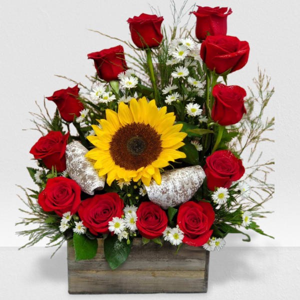 Arrangement of red roses, a large yellow sunflower, and small white daisies in a wooden box
