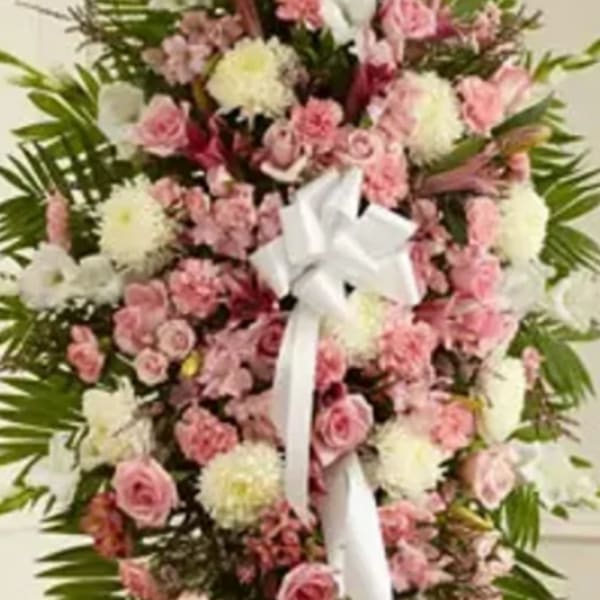Standing floral spray of pink and white flowers with a white ribbon