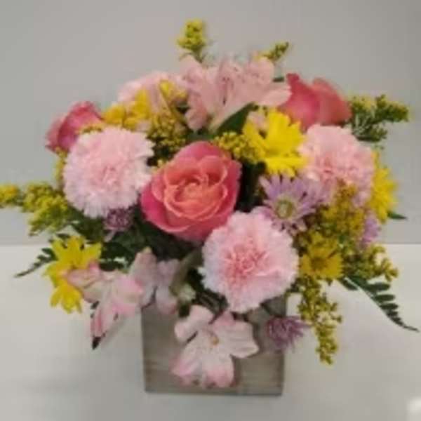 Pink and yellow mixed flower arrangement in a square vase