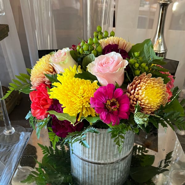 Mixed bouquet of roses, chrysanthemums, and zinnias in a ribbed metal container