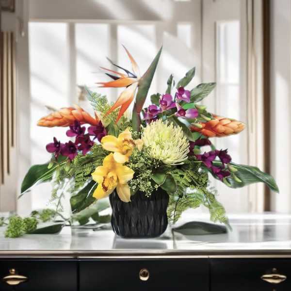 Tropical flower arrangement in a black vase with orange and purple blooms