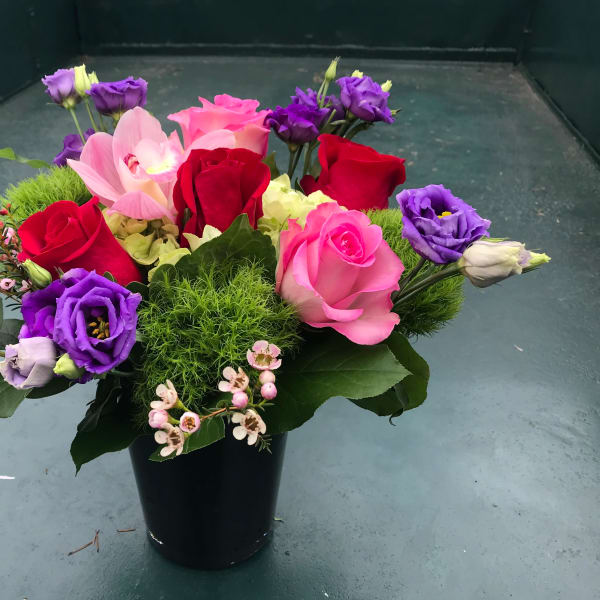 Mixed bouquet of roses and purple lisianthus in a black vase