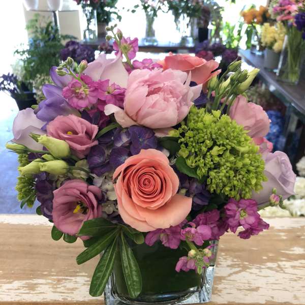 Mixed pink and purple bouquet in a square glass vase