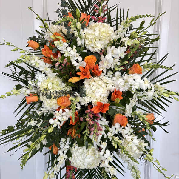 Large standing floral spray with white and orange flowers on a black easel