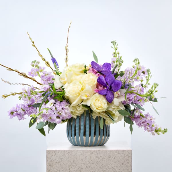Lavender and cream floral arrangement in a blue striped vase