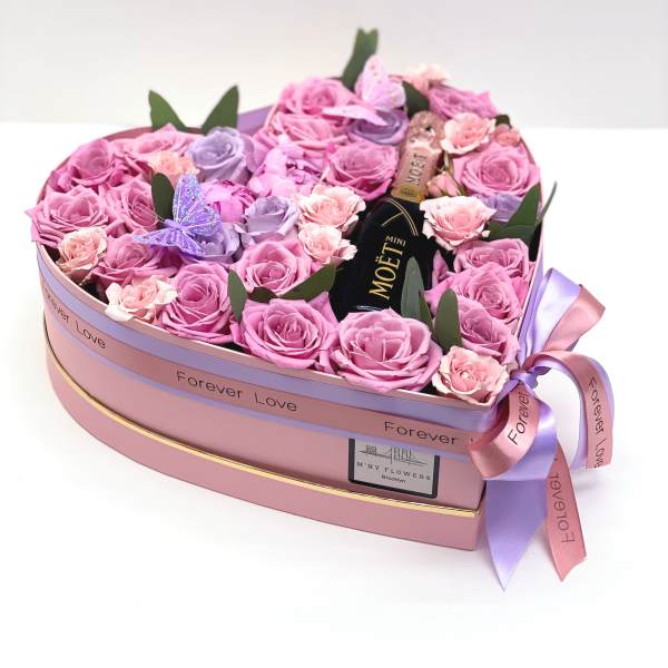Heart-shaped box of pink and lavender roses with a mini Moët bottle
